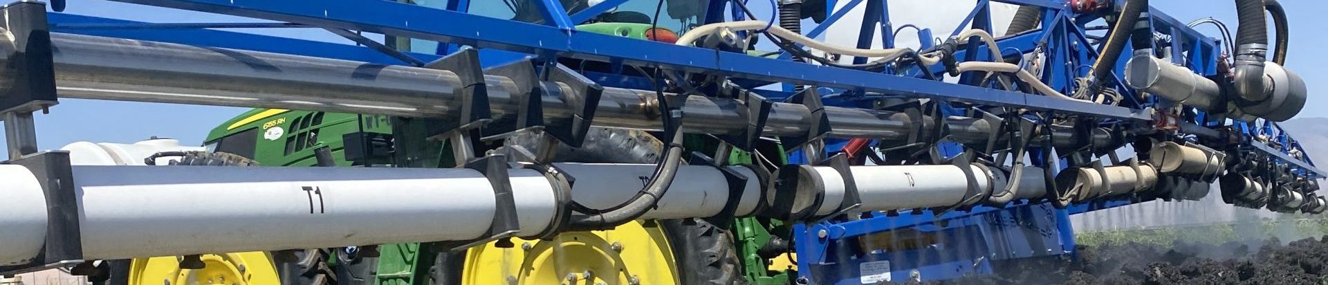 Close up of long OnTarget electrostatic sprayer going over a broccoli field