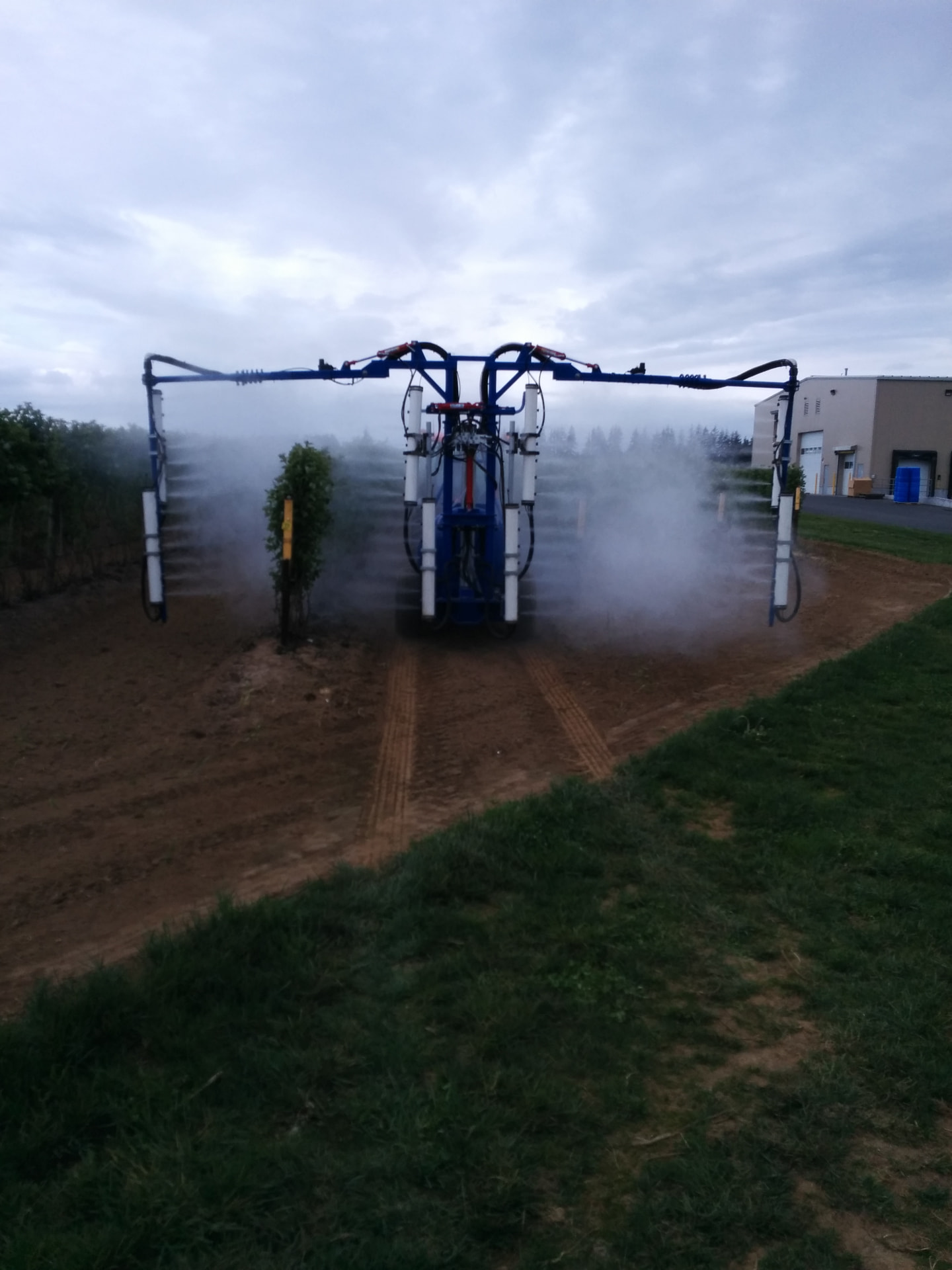 OnTarget sprayer with booms deployed producing a full wrap-around spray cloud during a water test