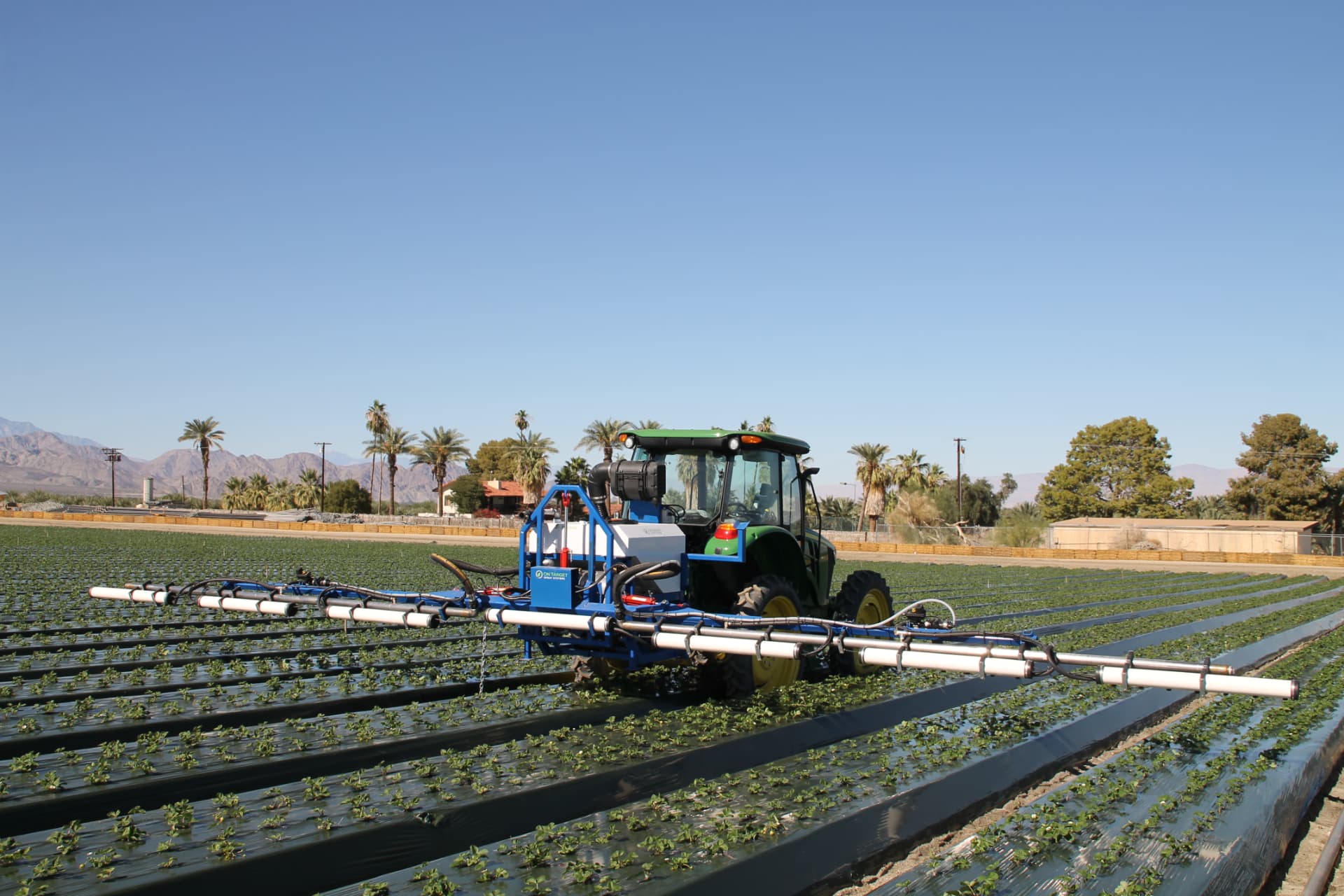 OnTarget multi-row boom sprayer parked in a desert strawberry field